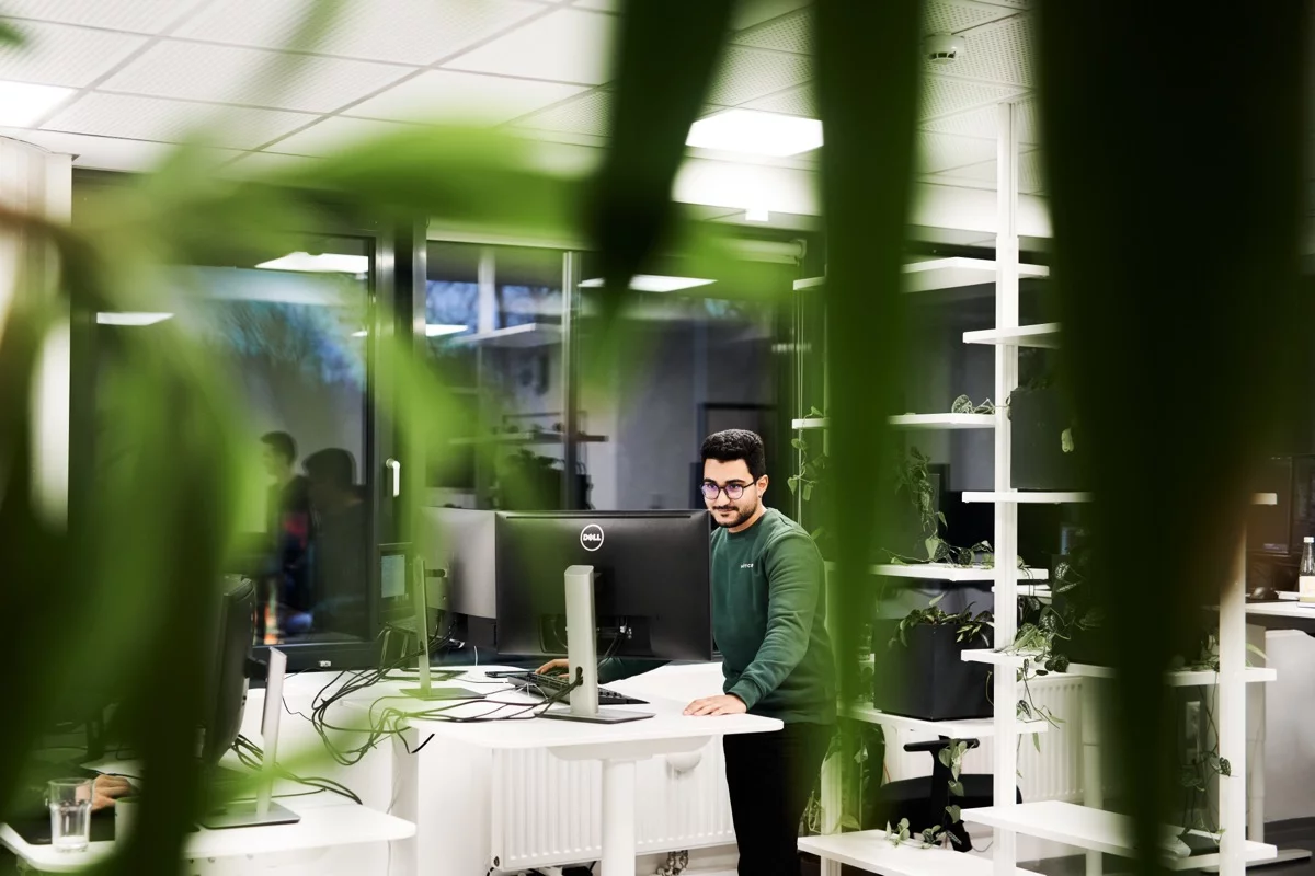 Developer standing at his desk, surrounded by plants